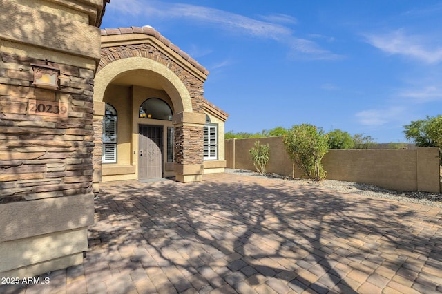 20239 N 39th Dr, Glendale, AZ 85308 - doorway to property featuring stucco siding, stone siding, a patio, and a tiled roof
