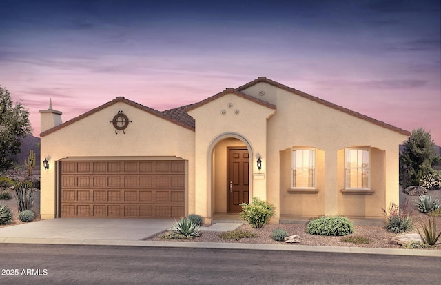 mediterranean / spanish home featuring driveway, an attached garage, a tile roof, and stucco siding