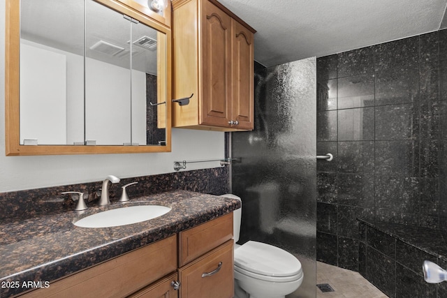 bathroom featuring vanity, a tile shower, a textured ceiling, and toilet