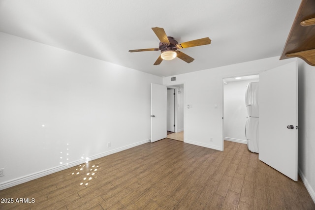 unfurnished bedroom with a walk in closet, white fridge, ceiling fan, and light hardwood / wood-style flooring