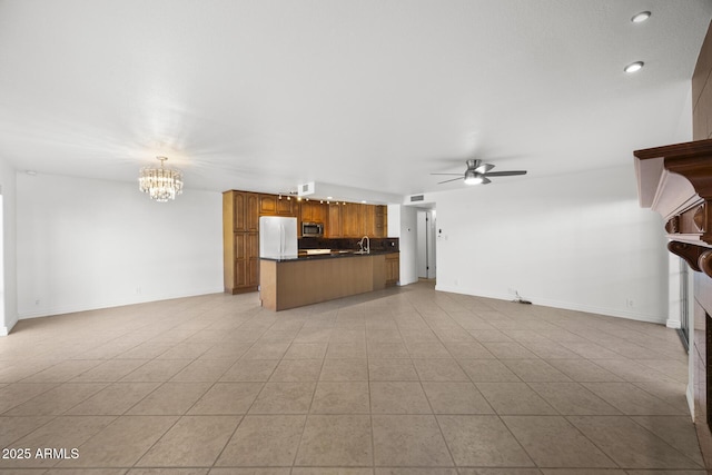 unfurnished living room with sink, ceiling fan with notable chandelier, and light tile patterned floors