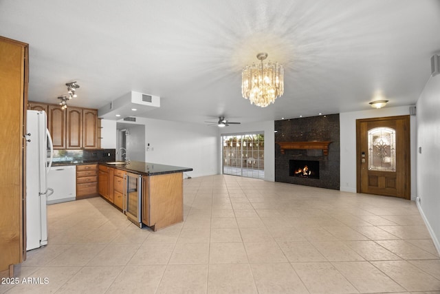 kitchen with wine cooler, sink, hanging light fixtures, kitchen peninsula, and white appliances