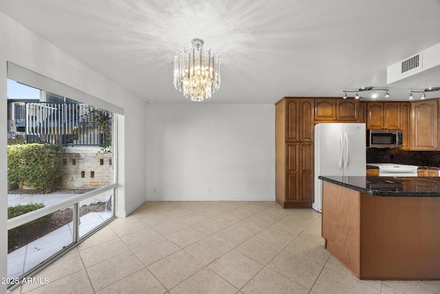 kitchen featuring pendant lighting, white appliances, dark stone countertops, and light tile patterned flooring