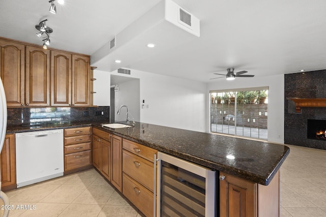 kitchen with beverage cooler, white dishwasher, kitchen peninsula, and sink