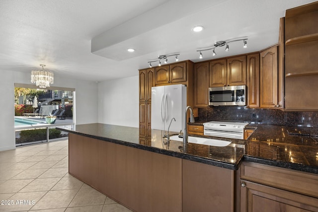 kitchen with pendant lighting, sink, white appliances, light tile patterned floors, and dark stone counters