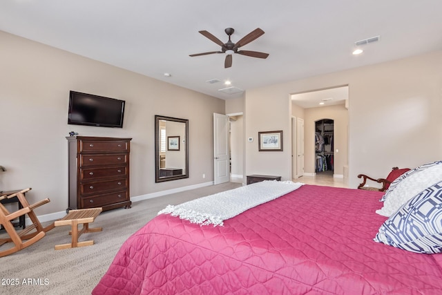 carpeted bedroom with a walk in closet and ceiling fan