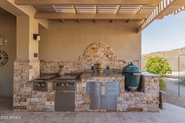 view of patio with exterior kitchen, area for grilling, and a pergola