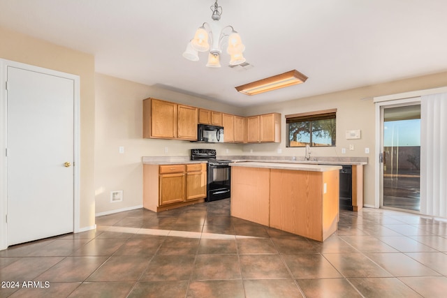 kitchen featuring dark tile patterned floors, black appliances, pendant lighting, a notable chandelier, and a kitchen island