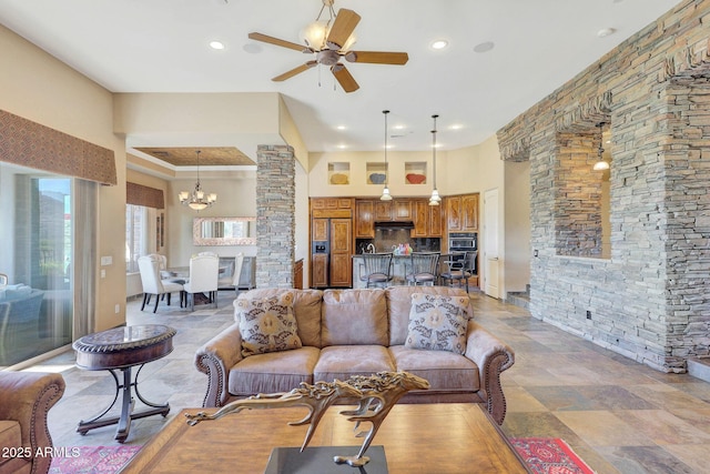 living room featuring a high ceiling and ceiling fan with notable chandelier