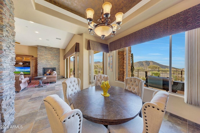 dining space with a mountain view, an outdoor stone fireplace, an inviting chandelier, and crown molding