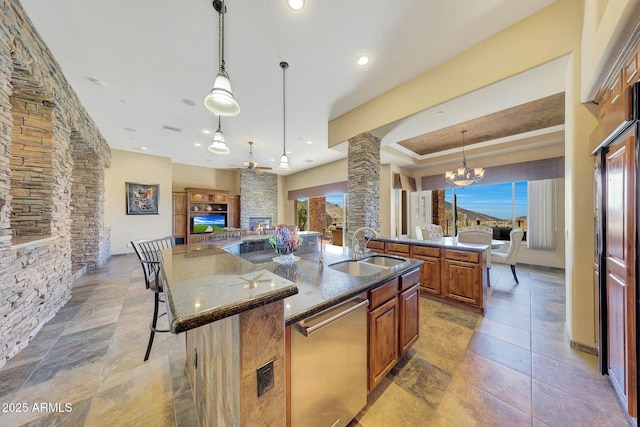 kitchen featuring a kitchen breakfast bar, hanging light fixtures, stainless steel dishwasher, a large island, and decorative columns