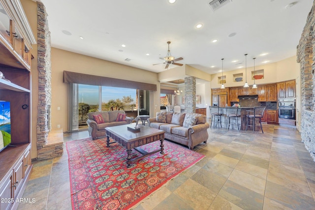 living room with a high ceiling, decorative columns, and ceiling fan