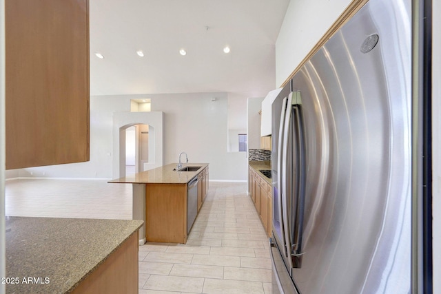 10253 E Indigo Dr, Scottsdale, AZ 85255 - kitchen with appliances with stainless steel finishes, backsplash, a sink, an island with sink, and arched walkways