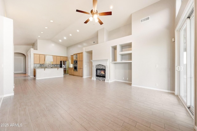 10253 E Indigo Dr, Scottsdale, AZ 85255 - unfurnished living room featuring ceiling fan, a glass covered fireplace, light wood-style floors, high vaulted ceiling, and recessed lighting