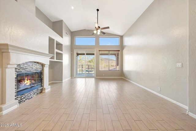 10253 E Indigo Dr, Scottsdale, AZ 85255 - unfurnished living room with ceiling fan, a tile fireplace, wood finished floors, baseboards, and high vaulted ceiling