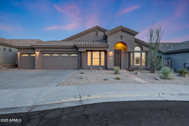 10253 E Indigo Dr, Scottsdale, AZ 85255 - mediterranean / spanish home featuring an attached garage, stucco siding, a tiled roof, and driveway