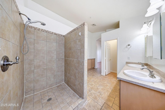 10253 E Indigo Dr, Scottsdale, AZ 85255 - full bathroom featuring tiled shower, double vanity, stone finish floors, and baseboards