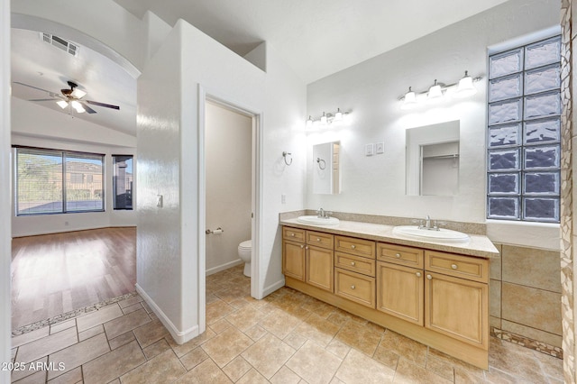 10253 E Indigo Dr, Scottsdale, AZ 85255 - bathroom featuring lofted ceiling, a ceiling fan, double vanity, toilet, and baseboards