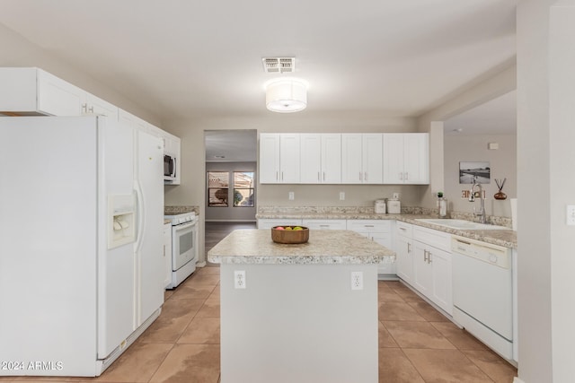 kitchen with light tile patterned flooring, sink, white cabinetry, a kitchen island, and white appliances