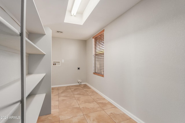 laundry area featuring hookup for a washing machine, light tile patterned floors, electric dryer hookup, and a skylight