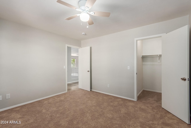 unfurnished bedroom featuring carpet flooring, ceiling fan, a walk in closet, and a closet