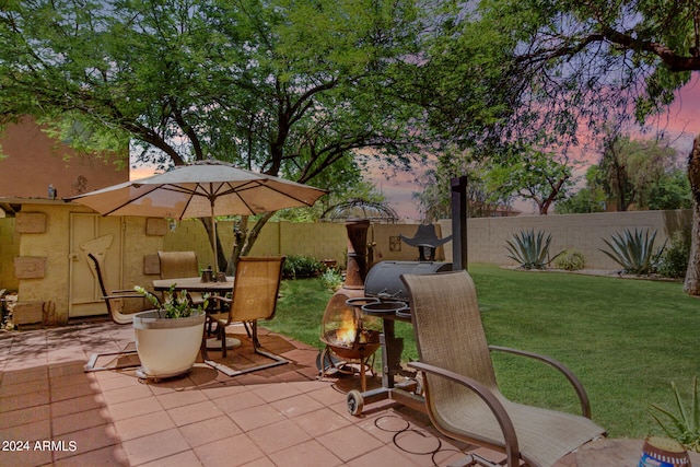 patio terrace at dusk featuring a yard