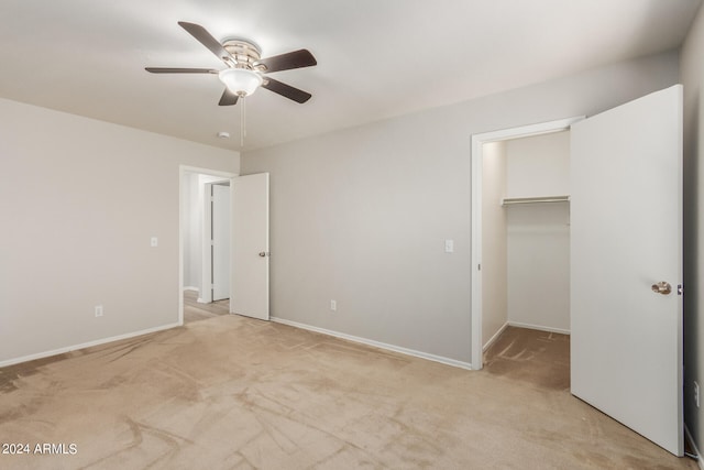 unfurnished bedroom featuring ceiling fan, a closet, light carpet, and a walk in closet