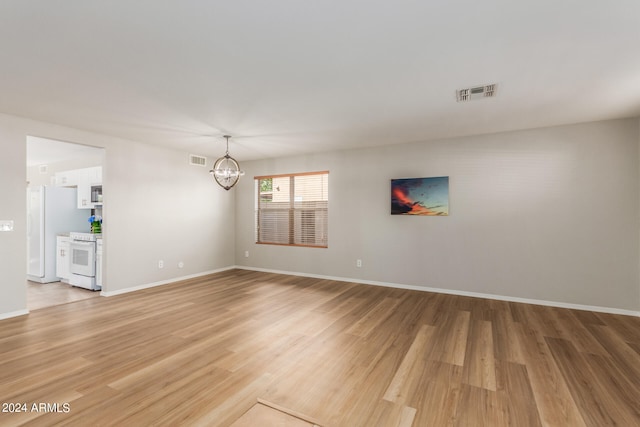 unfurnished living room featuring light hardwood / wood-style flooring and an inviting chandelier