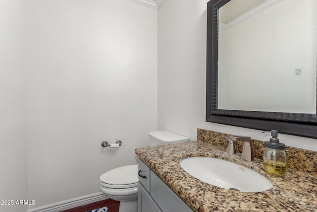 bathroom featuring ornamental molding, toilet, vanity, and baseboards