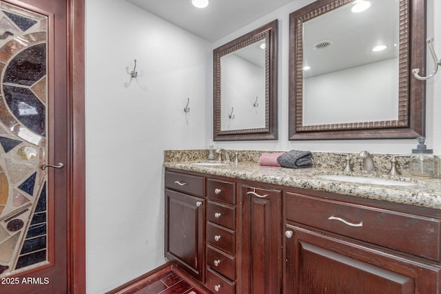 bathroom with double vanity, wood finished floors, and baseboards