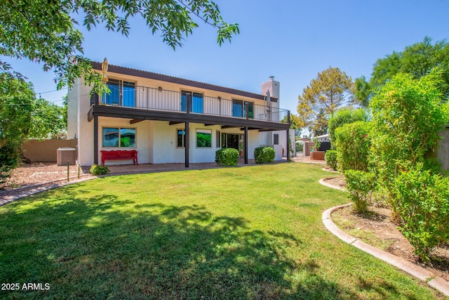 back of property with a balcony, stucco siding, a chimney, central air condition unit, and a patio