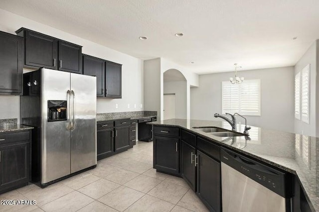 kitchen with dark stone countertops, appliances with stainless steel finishes, sink, light tile patterned floors, and decorative light fixtures