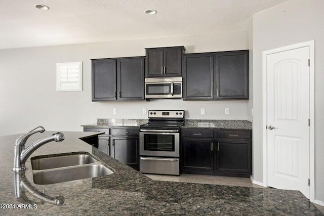 kitchen featuring dark stone countertops, appliances with stainless steel finishes, sink, and light tile patterned floors