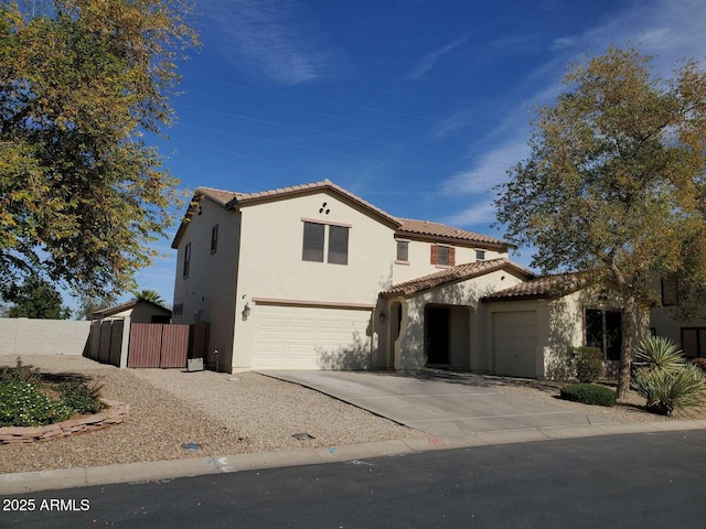 mediterranean / spanish house with a tile roof, stucco siding, concrete driveway, an attached garage, and fence