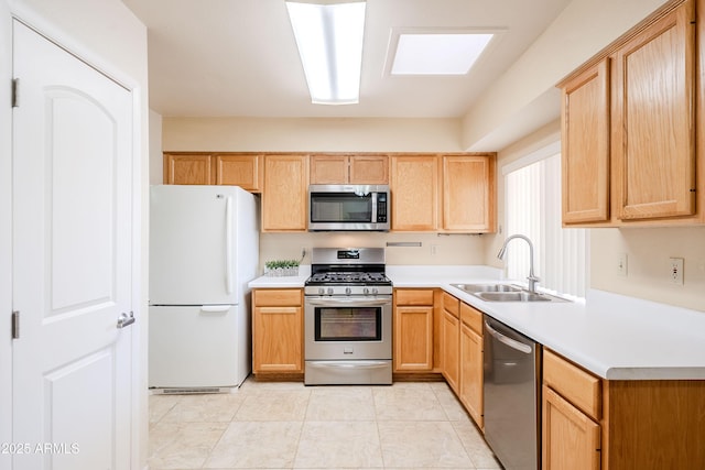 kitchen featuring sink, a skylight, appliances with stainless steel finishes, and light brown cabinets