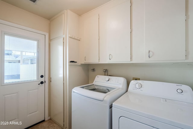 clothes washing area with washer and clothes dryer, light tile patterned floors, and cabinets