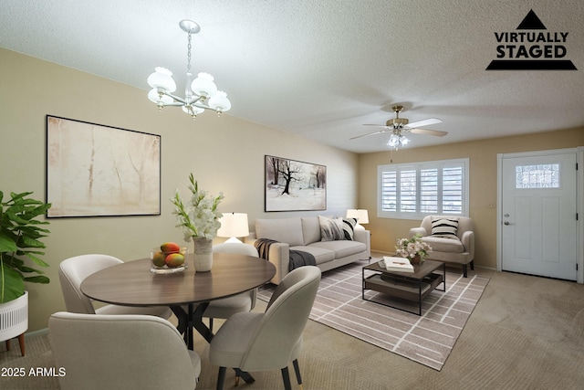 carpeted dining area featuring ceiling fan with notable chandelier and a textured ceiling