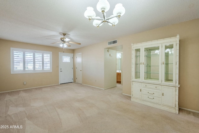 interior space with ceiling fan with notable chandelier, light colored carpet, and a textured ceiling