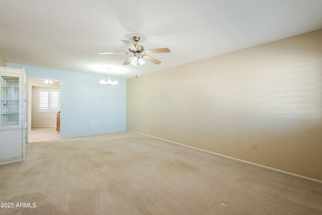 carpeted spare room featuring ceiling fan with notable chandelier and a textured ceiling