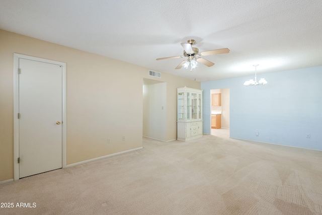 unfurnished room with light carpet, ceiling fan with notable chandelier, and a textured ceiling