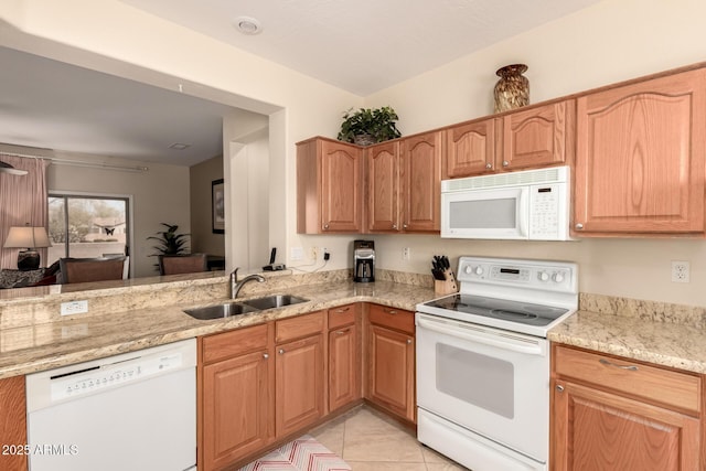 kitchen with a sink, white appliances, light stone counters, and light tile patterned floors