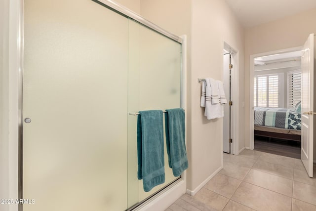 ensuite bathroom with tile patterned flooring, a shower stall, baseboards, and ensuite bathroom