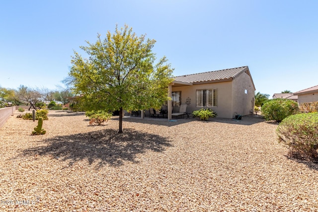 rear view of property featuring stucco siding, a tile roof, and a patio