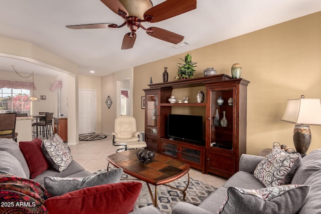 living room featuring light tile patterned floors, visible vents, and ceiling fan