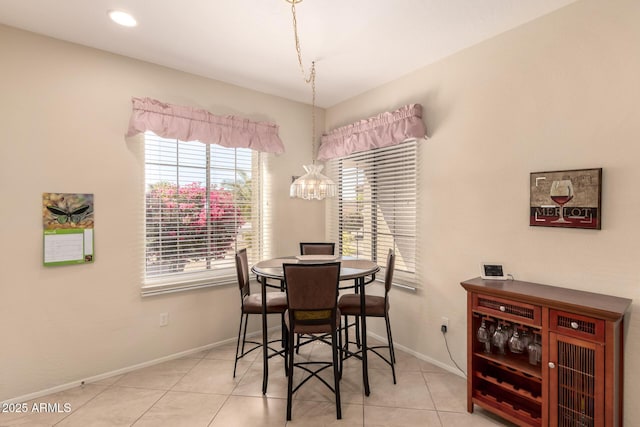tiled dining area featuring a notable chandelier and baseboards