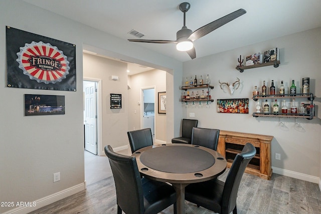 dining space with ceiling fan, indoor bar, washer / clothes dryer, and hardwood / wood-style floors