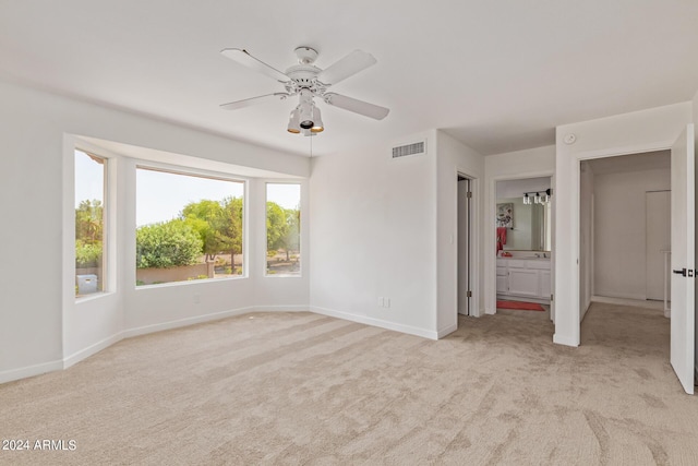 unfurnished bedroom featuring ceiling fan, connected bathroom, and light carpet