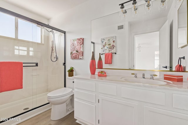 bathroom with vanity, toilet, hardwood / wood-style floors, and a shower with door