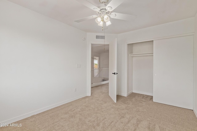 unfurnished bedroom featuring light carpet, a closet, and ceiling fan