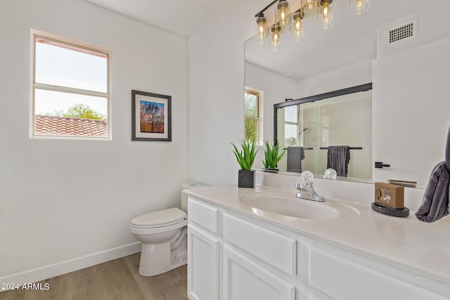 bathroom with hardwood / wood-style flooring, toilet, an enclosed shower, and vanity